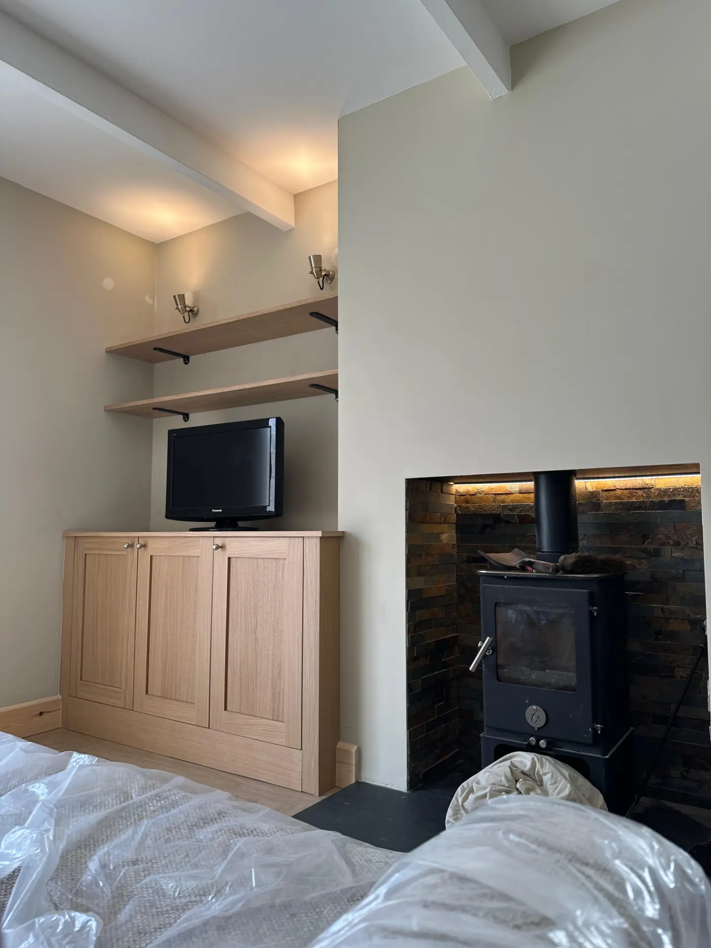 Alcove shelf accent wall lights and log burner recess lighting installed in a domestic living room